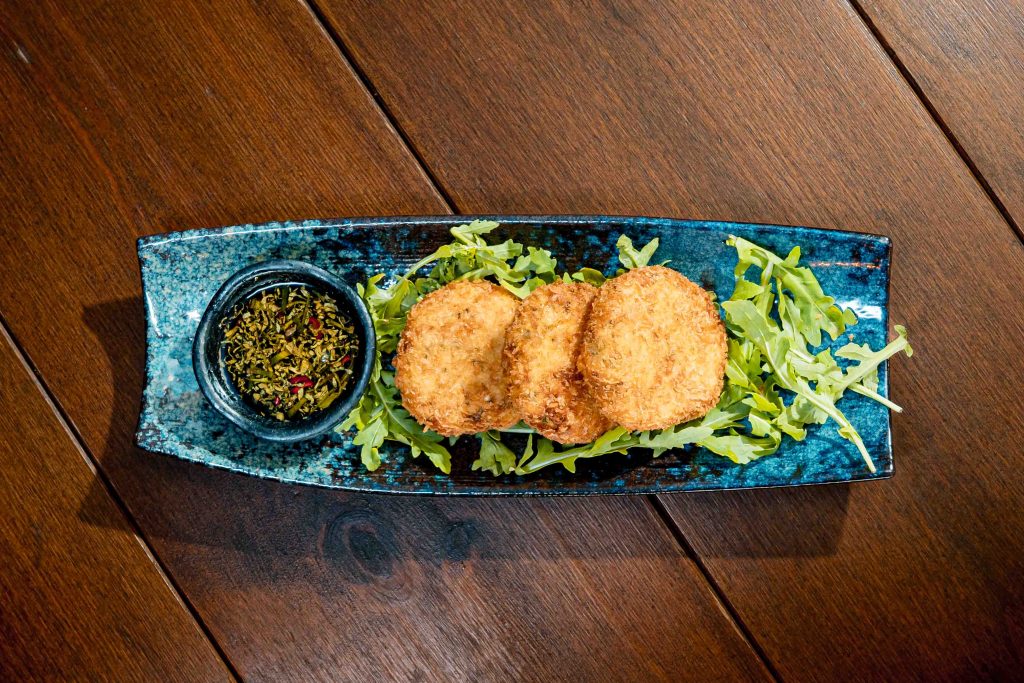 Courgette cakes on a bed of rocket with spicy sauce