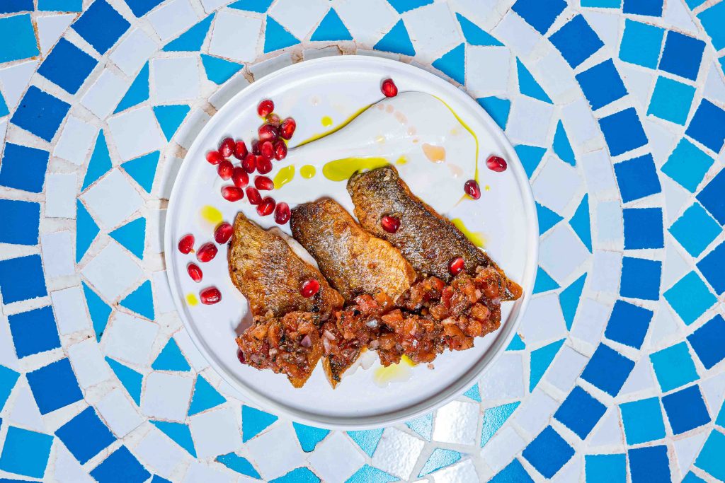 Seabass with tahini and bergamot sauce, roasted tomato chimichurri & pomegranate